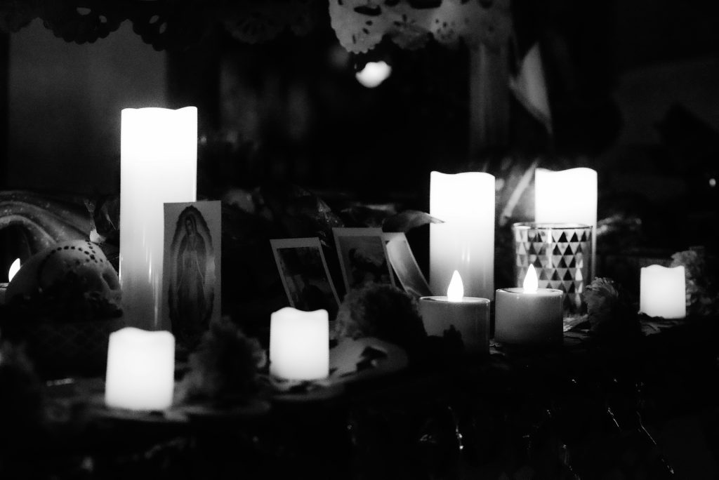 A person casting a spell at an altar with candles, crystals, and herbs